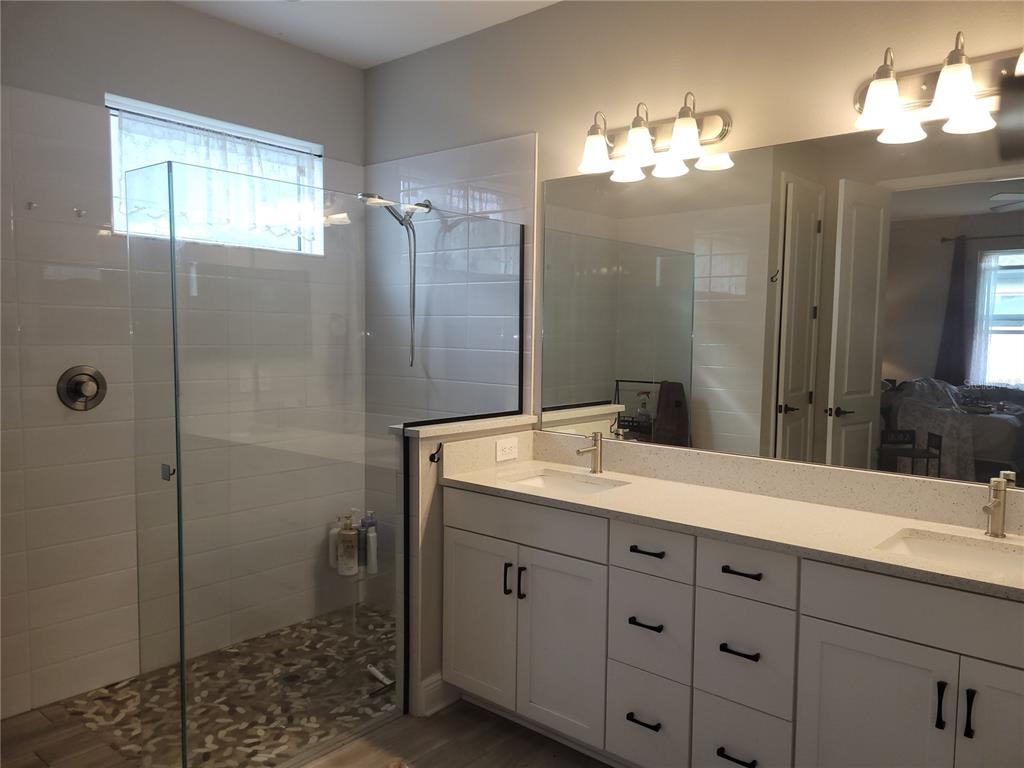 A bathroom features a glass-enclosed walk-in shower, a double vanity with white cabinets, and mirrors — 12571 NIGHT VIEW DRIVE, SARASOTA, FL