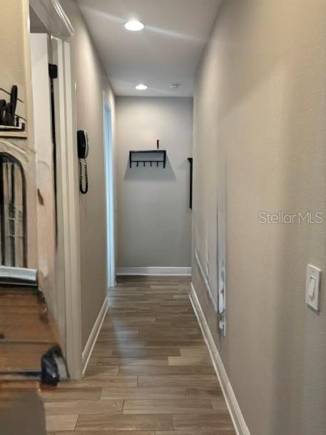 A hallway features light wood-look flooring, recessed lighting, and a wall-mounted coat rack — 12571 NIGHT VIEW DRIVE, SARASOTA, FL