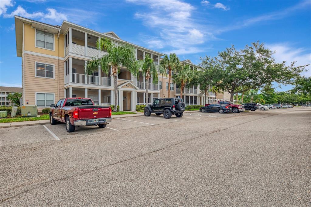 A three-story apartment building with a parking lot in the foreground — 4802 51ST STREET W UNIT 1903, BRADENTON, FL