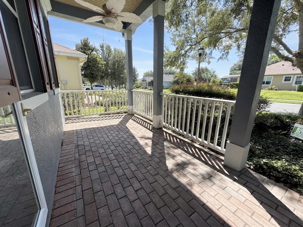 A covered front porch features brick pavers, white railings, and a ceiling fan — 129 CREPE MYRTLE DRIVE, GROVELAND, FL