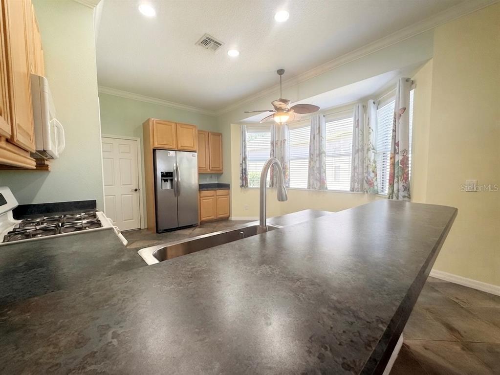 A kitchen features a dark countertop island, stainless steel appliances, and a bay window breakfast area — 129 CREPE MYRTLE DRIVE, GROVELAND, FL