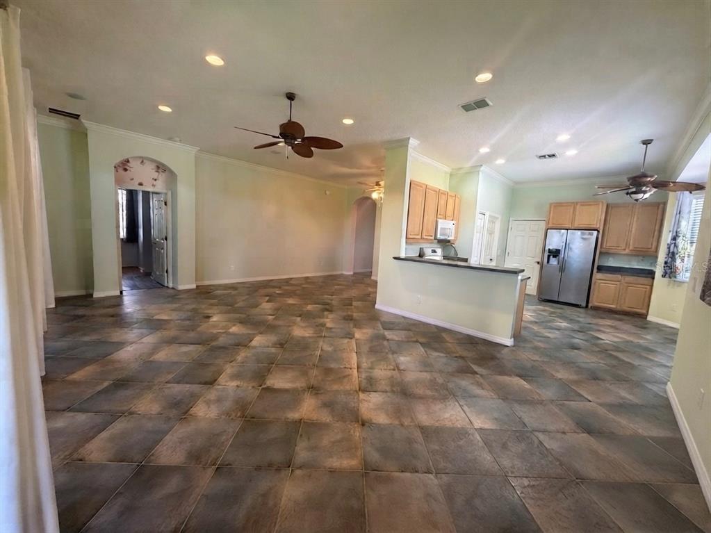 An open-concept living area features large square floor tiles and a kitchen with wooden cabinets — 129 CREPE MYRTLE DRIVE, GROVELAND, FL