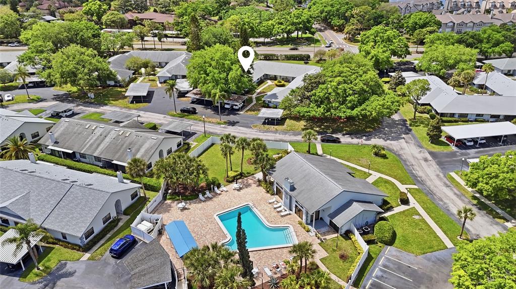 An aerial view shows a community pool, clubhouse, and surrounding residential buildings with parking areas — 2701 COUNTRYSIDE BOULEVARD UNIT 101, CLEARWATER, FL