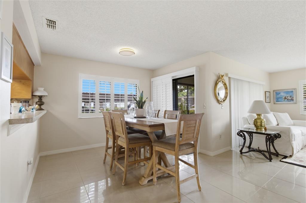 A dining area with a wooden table and chairs sits adjacent to a living room — 2701 COUNTRYSIDE BOULEVARD UNIT 101, CLEARWATER, FL