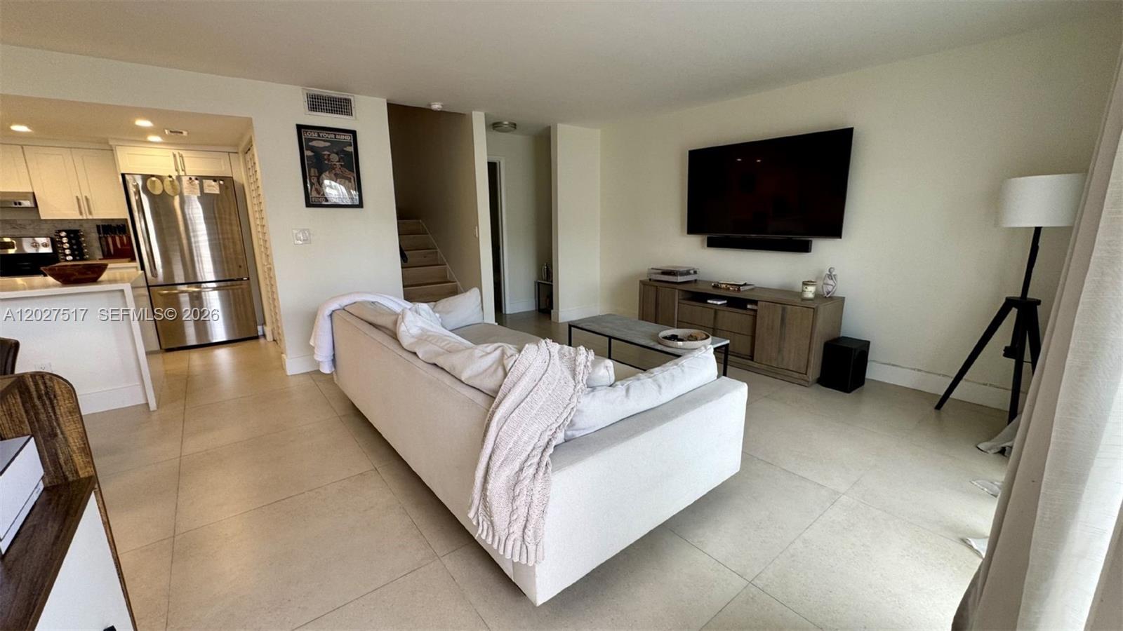 A living room features a light-colored sofa, a wall-mounted television, and an adjacent kitchen — 4540 SW 68th Ct Cir # 7, Miami FL 33155, MIAMI, FL