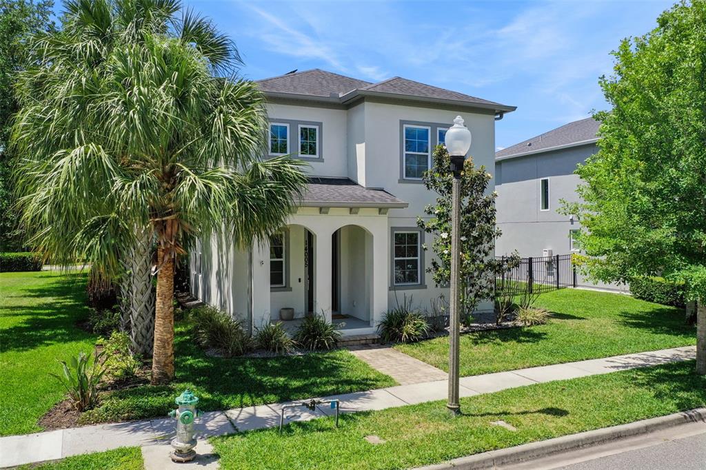 A two-story stucco house with a covered entryway, palm tree, and street lamp — 14005 ALDFORD DRIVE, WINTER GARDEN, FL