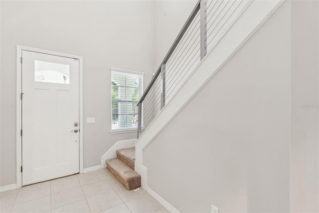 An entryway features light tile flooring, a white front door, and stairs with metal railings — 14005 ALDFORD DRIVE, WINTER GARDEN, FL