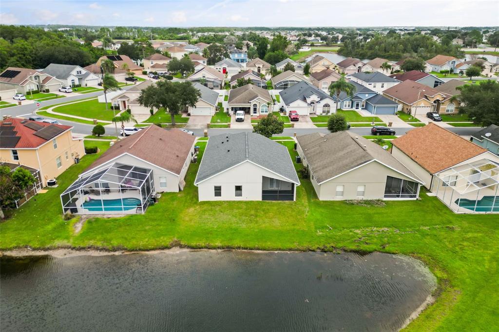 An aerial view shows a row of suburban houses with backyards facing a small pond — 2608 DECK AVENUE, KISSIMMEE, FL
