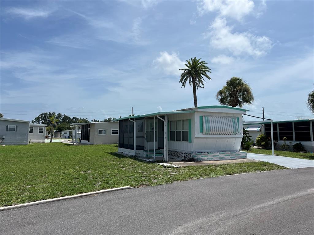 A white mobile home with a screened-in porch sits on a grassy lot — 634 COMO DRIVE, VENICE, FL