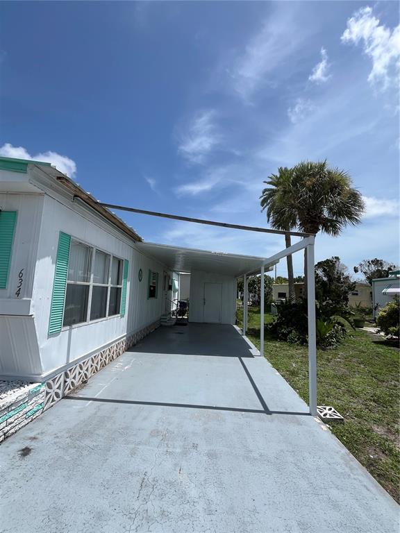 A mobile home exterior features a painted concrete driveway and a metal carport structure — 634 COMO DRIVE, VENICE, FL