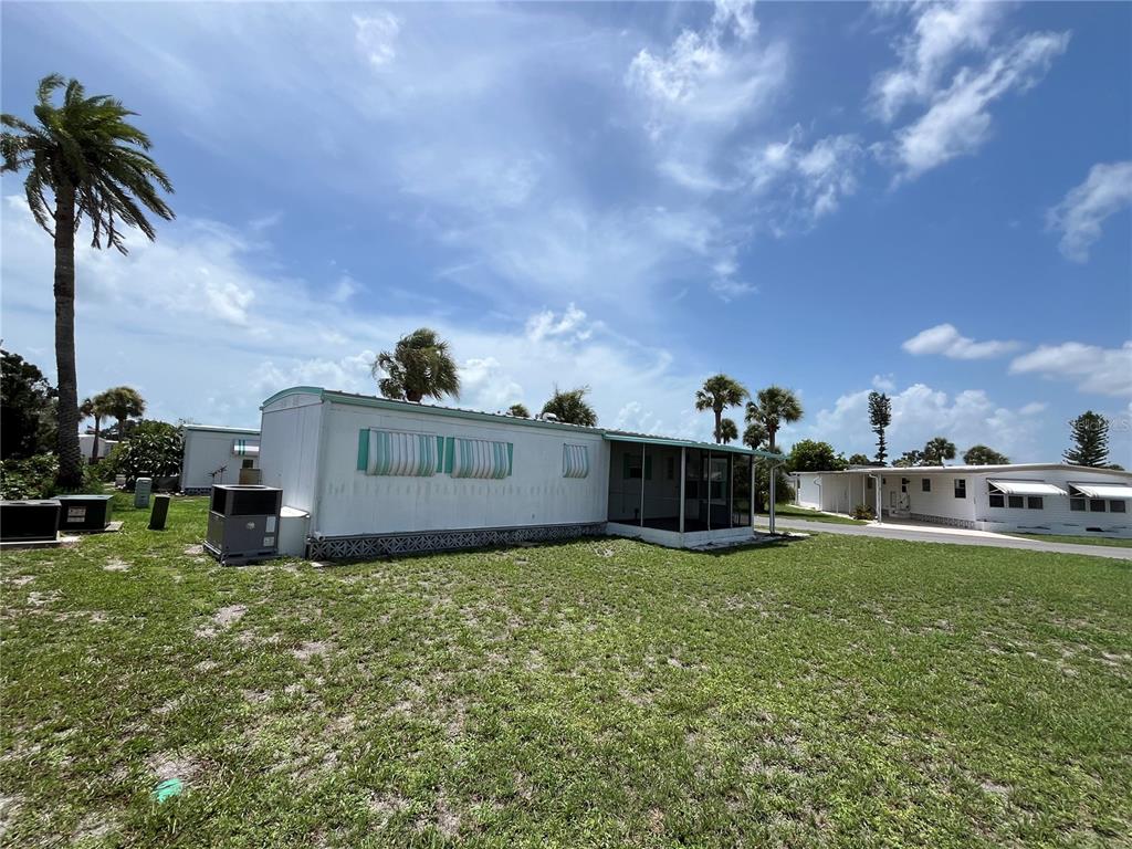 A mobile home with a screened-in porch sits on a grassy lot with palm trees — 634 COMO DRIVE, VENICE, FL