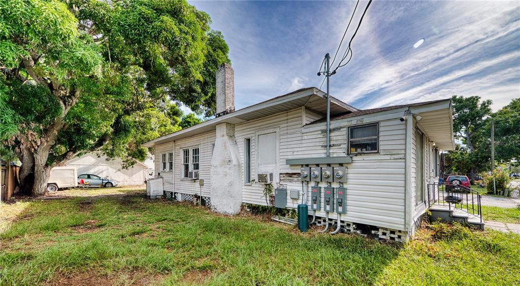 A white, single-story house with a brick chimney and multiple electrical meters on the exterior — 1514 12TH AVENUE W, BRADENTON, FL