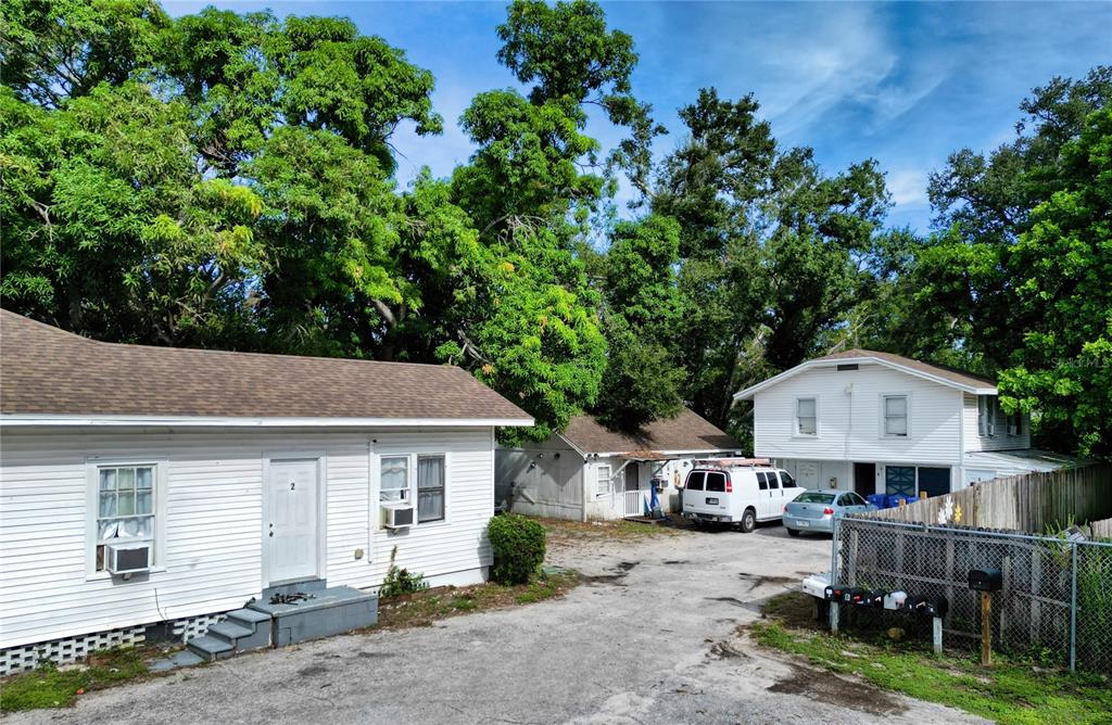 A gravel driveway leads to several white residential buildings surrounded by mature trees — 1514 12TH AVENUE W, BRADENTON, FL