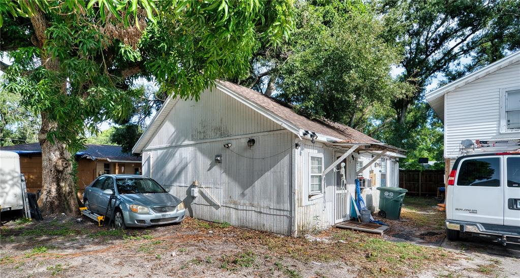 A white detached structure sits on a dirt lot next to a parked car — 1514 12TH AVENUE W, BRADENTON, FL