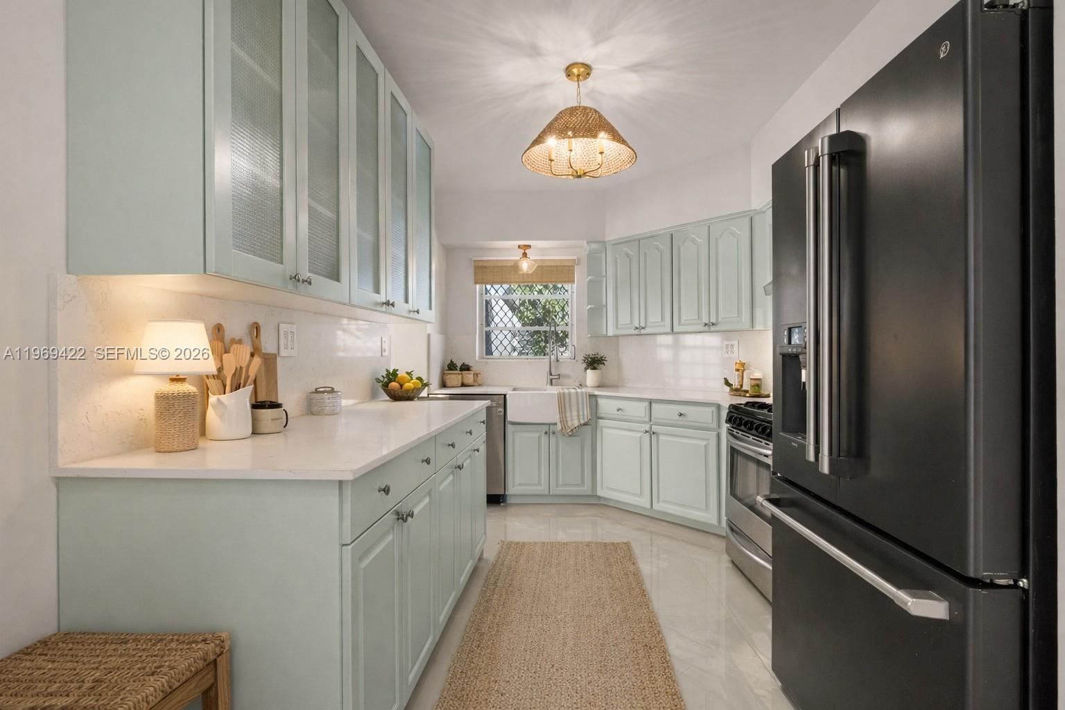A kitchen features light blue cabinets, white countertops, a farmhouse sink, and a black refrigerator — 9241 Marine Dr, Cutler Bay FL 33189, CUTLER BAY, FL