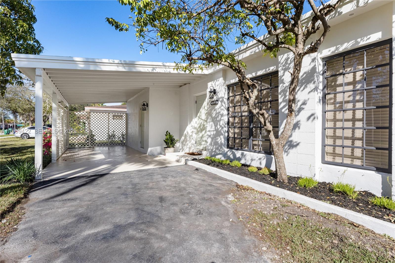 A white house exterior features a carport, a lattice privacy screen, and dark-framed windows — 9241 Marine Dr, Cutler Bay FL 33189, CUTLER BAY, FL
