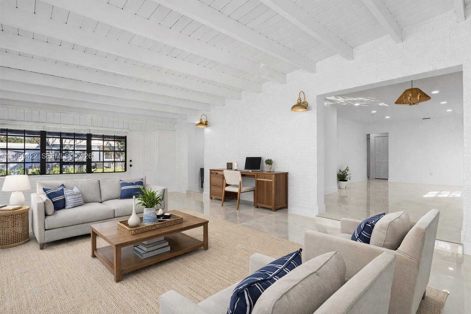A bright living room features white brick walls, exposed ceiling beams, and a wooden desk — 9241 Marine Dr, Cutler Bay FL 33189, CUTLER BAY, FL