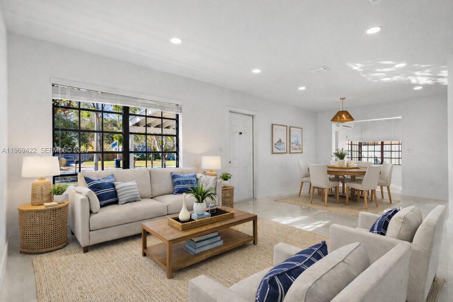A bright living and dining area features light-colored furniture, a wooden coffee table, and windows — 9241 Marine Dr, Cutler Bay FL 33189, CUTLER BAY, FL
