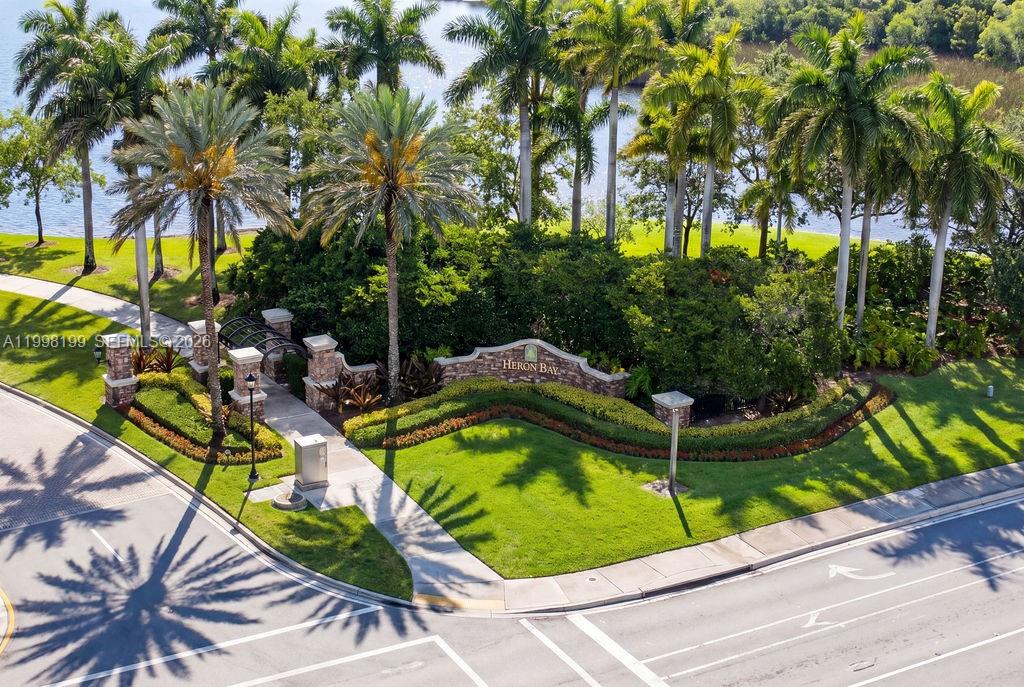 An aerial view shows the Heron Bay community entrance with palm trees, landscaping, and signage — 8055 NW 117th Way, Parkland FL 33076, PARKLAND, FL