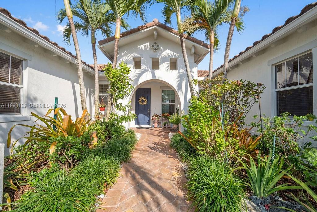 A brick walkway leads to the blue front door of a white stucco house — 8055 NW 117th Way, Parkland FL 33076, PARKLAND, FL