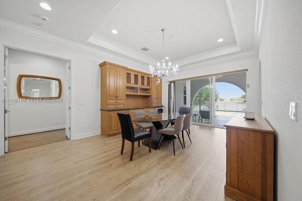 A dining room features light wood flooring, a built-in hutch, and sliding glass doors — 8055 NW 117th Way, Parkland FL 33076, PARKLAND, FL