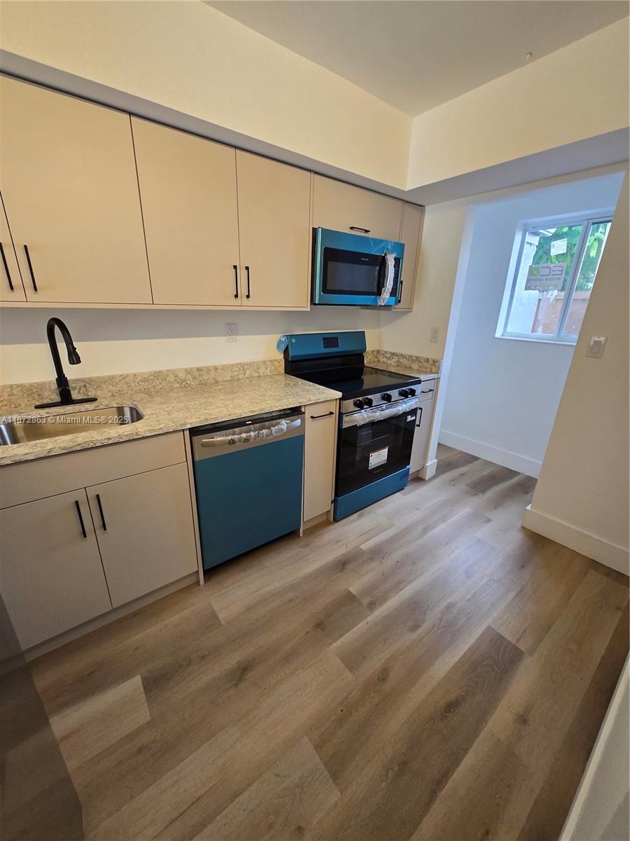A kitchen features light-colored cabinets, stainless steel appliances, and wood-look flooring — 15124 SW 81st St # 102, Miami FL 33193, MIAMI, FL
