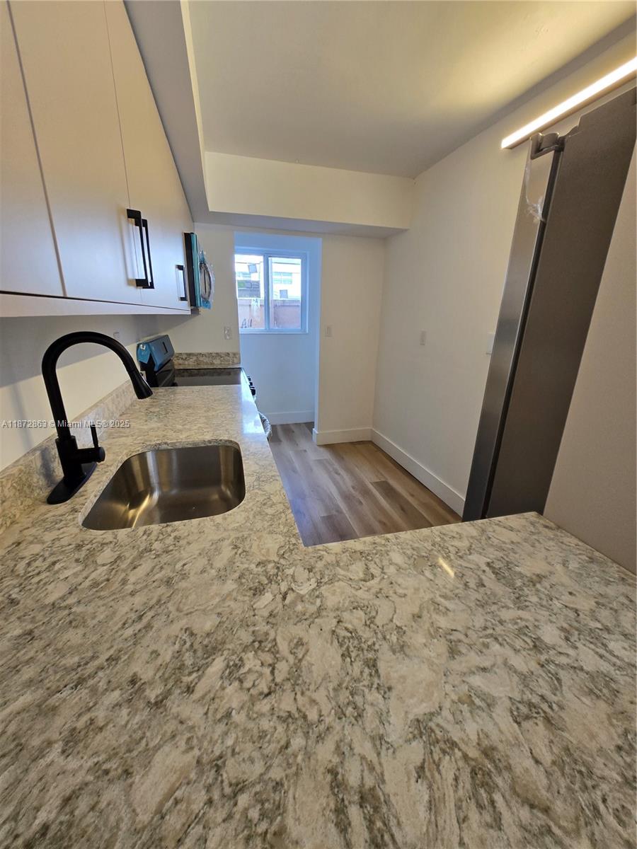 A kitchen features light-colored cabinets, granite countertops, a stainless steel sink, and wood-look flooring — 15124 SW 81st St # 102, Miami FL 33193, MIAMI, FL