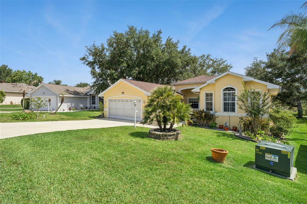 A yellow single-story house with a two-car garage and a green utility box in front — 21325 ROYAL TROON DRIVE, LEESBURG, FL