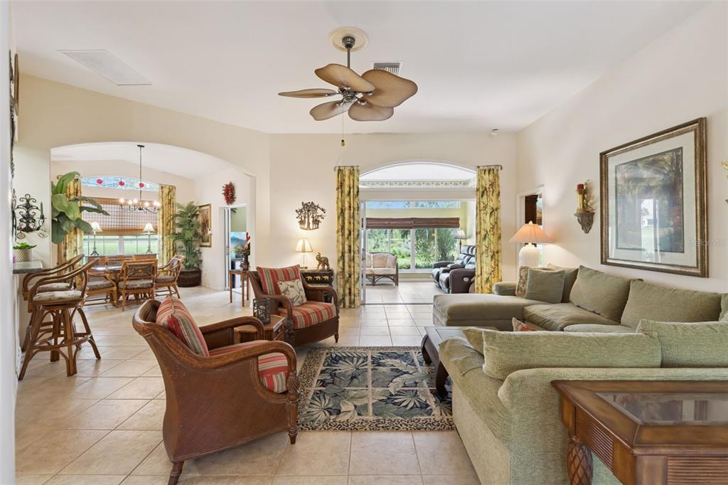 A spacious living room with tile floors, a ceiling fan, and a view of the patio — 21325 ROYAL TROON DRIVE, LEESBURG, FL