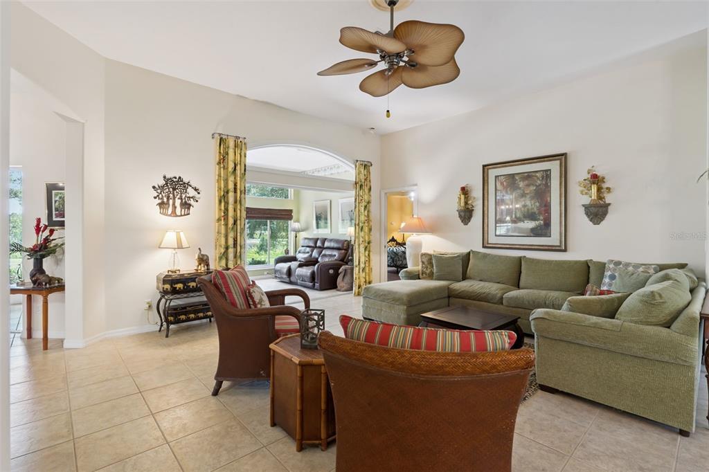 A living room features a green sectional sofa, two armchairs, and a tropical ceiling fan — 21325 ROYAL TROON DRIVE, LEESBURG, FL