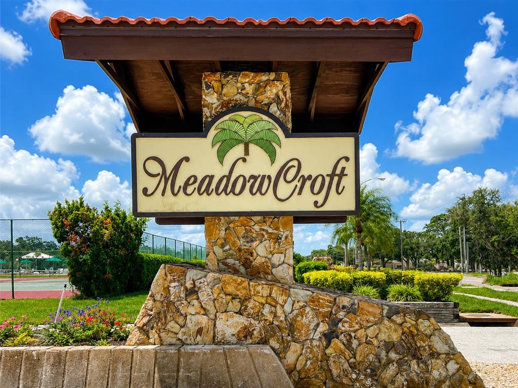 A stone monument sign with a palm tree logo identifies the Meadow Croft community — 1435 57TH STREET W UNIT 1435, BRADENTON, FL
