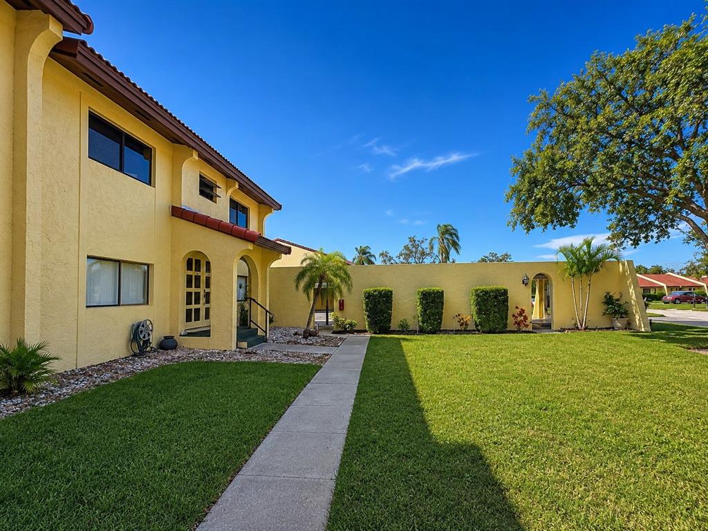A yellow two-story building with a walkway leading to the entrance and a grassy yard — 1435 57TH STREET W UNIT 1435, BRADENTON, FL
