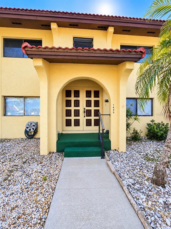 The exterior of a yellow two-story building features a covered entryway with double doors — 1435 57TH STREET W UNIT 1435, BRADENTON, FL