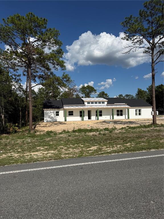 A newly constructed white single-story house with a dark roof sits on a sandy lot — 13989 SW 89TH STREET, DUNNELLON, FL