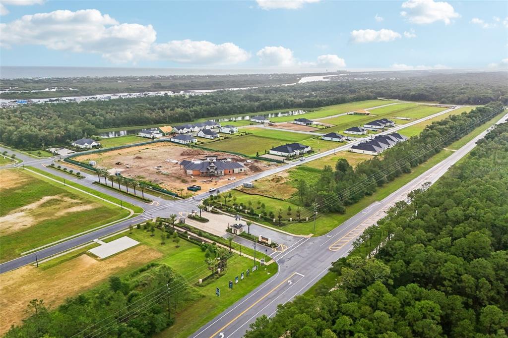 An aerial view shows a residential development under construction with houses, roads, and surrounding woods — 160 CORONADO ROAD, FLAGLER BEACH, FL