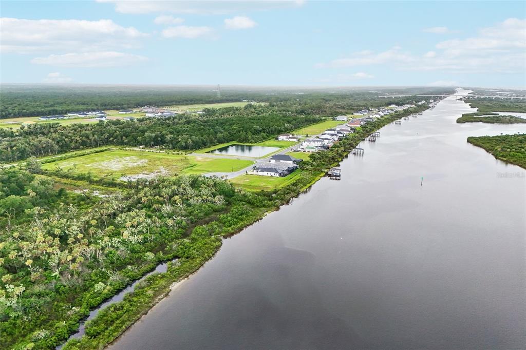 An aerial view shows houses situated along a riverbank next to a large wooded area — 160 CORONADO ROAD, FLAGLER BEACH, FL