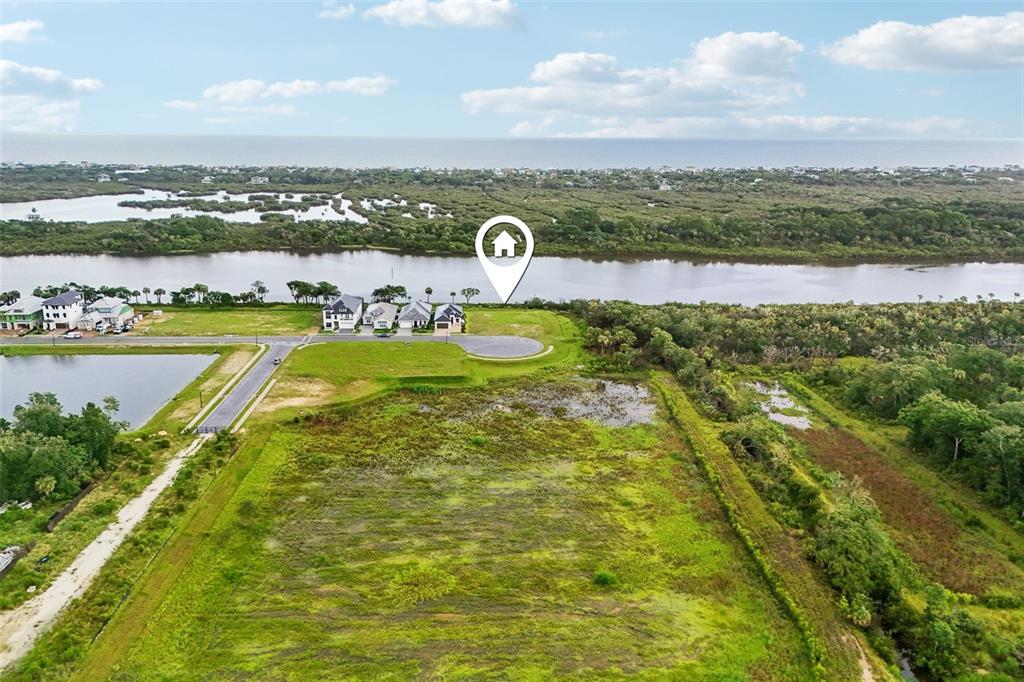 An aerial view shows a vacant lot near a row of houses and a river — 160 CORONADO ROAD, FLAGLER BEACH, FL