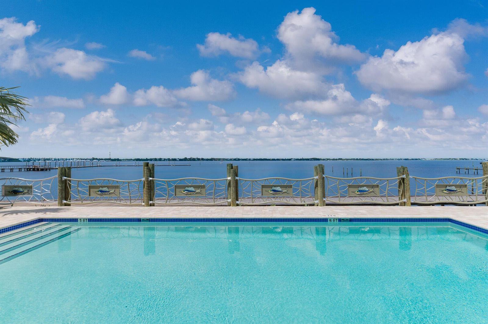 A swimming pool overlooks a calm body of water with a decorative wooden fence — 41 SW Seminole Street # 305, Stuart FL 34994, STUART, FL