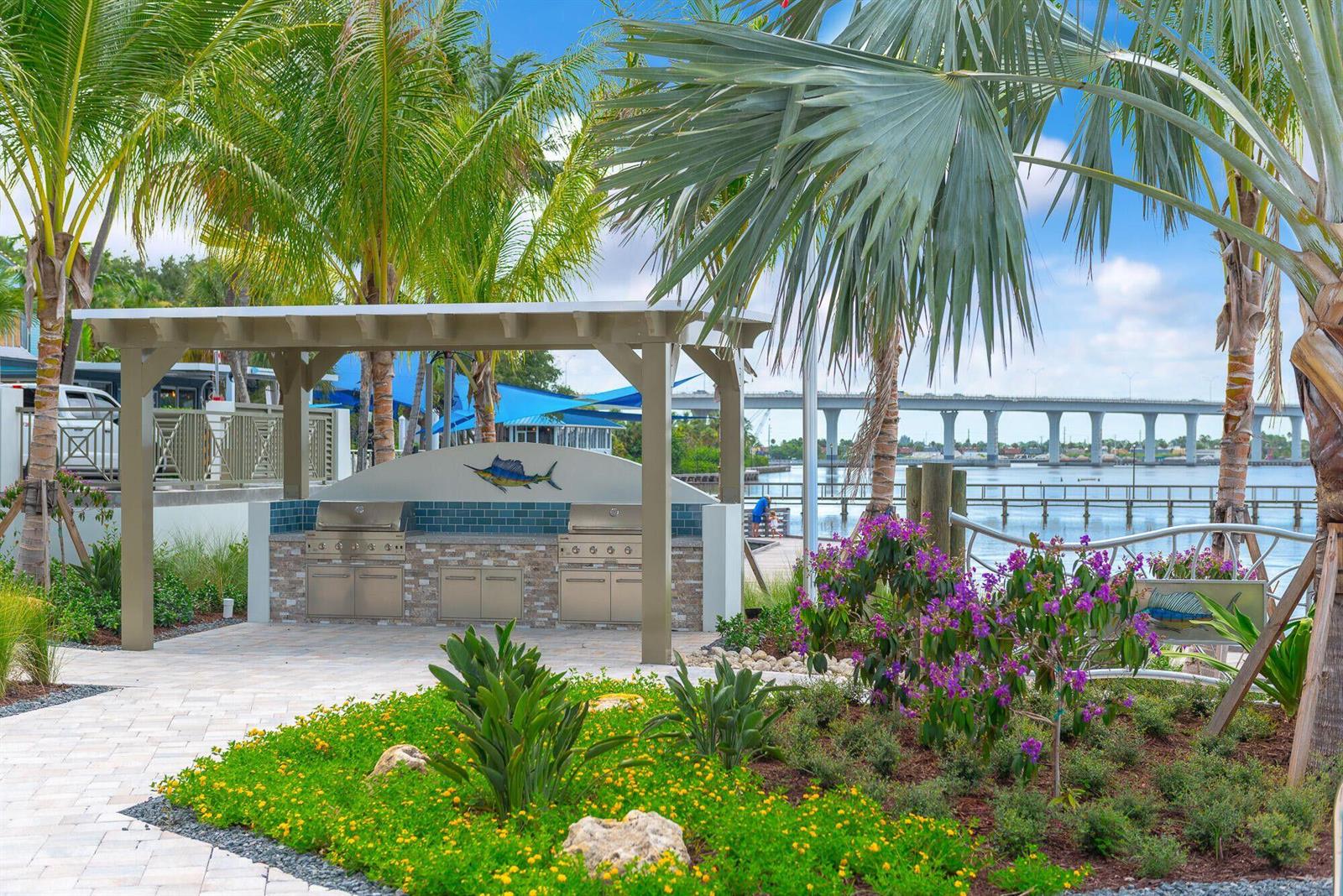 An outdoor kitchen with two stainless steel grills sits under a pergola near a waterfront — 41 SW Seminole Street # 305, Stuart FL 34994, STUART, FL