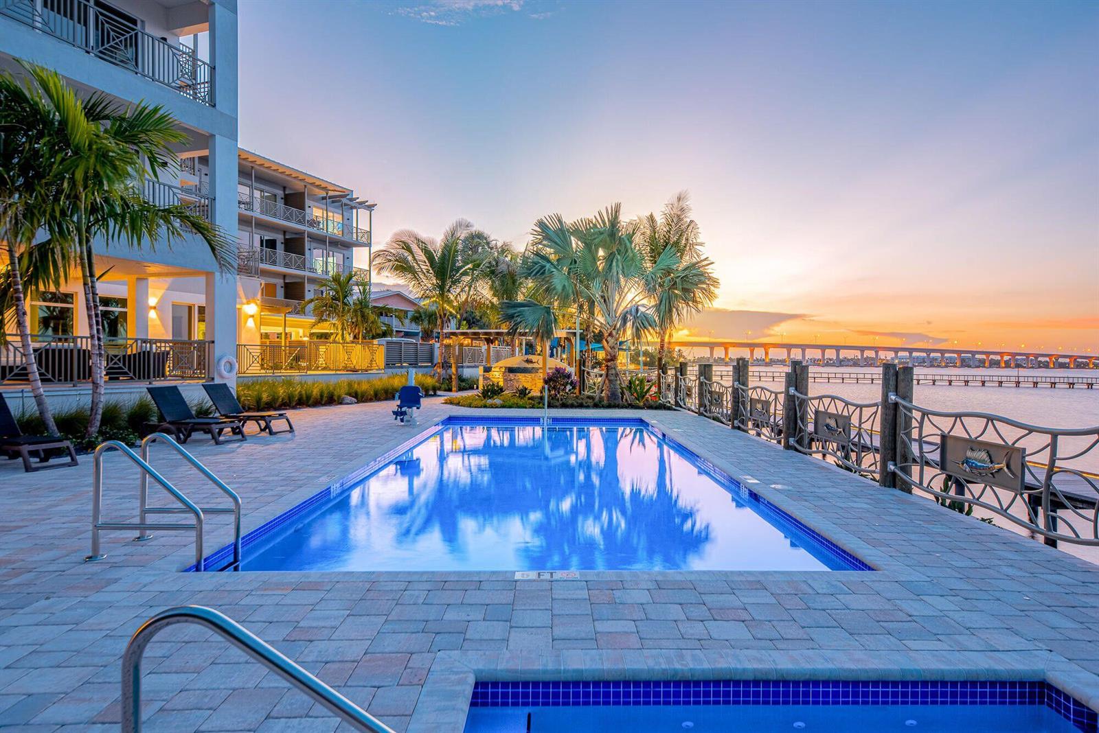 A swimming pool and hot tub overlook a bay with a bridge at sunset — 41 SW Seminole Street # 305, Stuart FL 34994, STUART, FL
