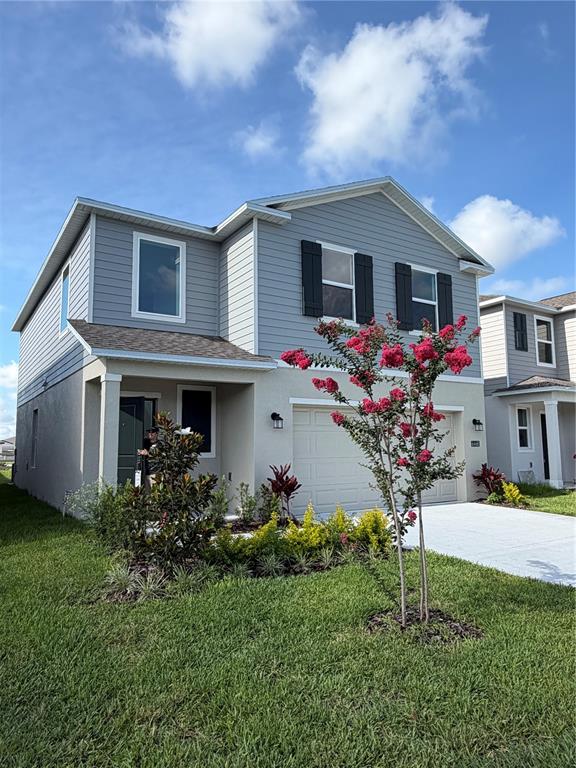 A two-story house with gray siding, a garage, and a blooming crape myrtle tree — 6468 DOMIZIO DRIVE, WINTER HAVEN, FL