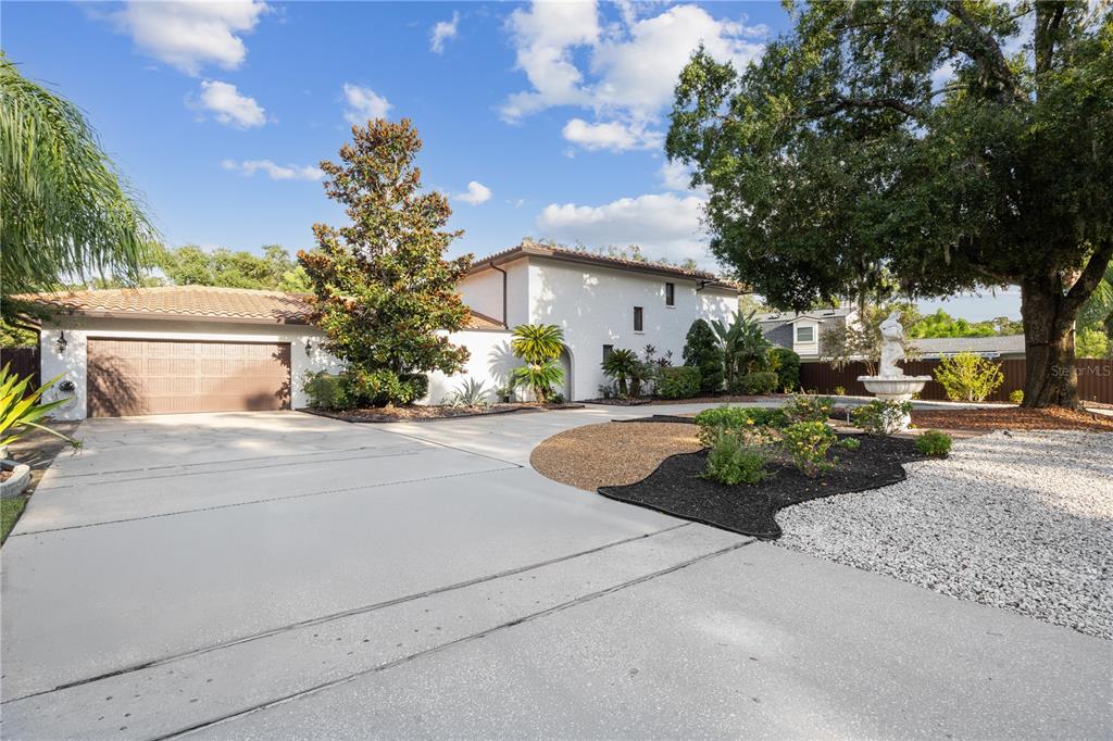 A white stucco house with a tiled roof features a large driveway and a fountain — 403 WEEBURN ROAD, TEMPLE TERRACE, FL
