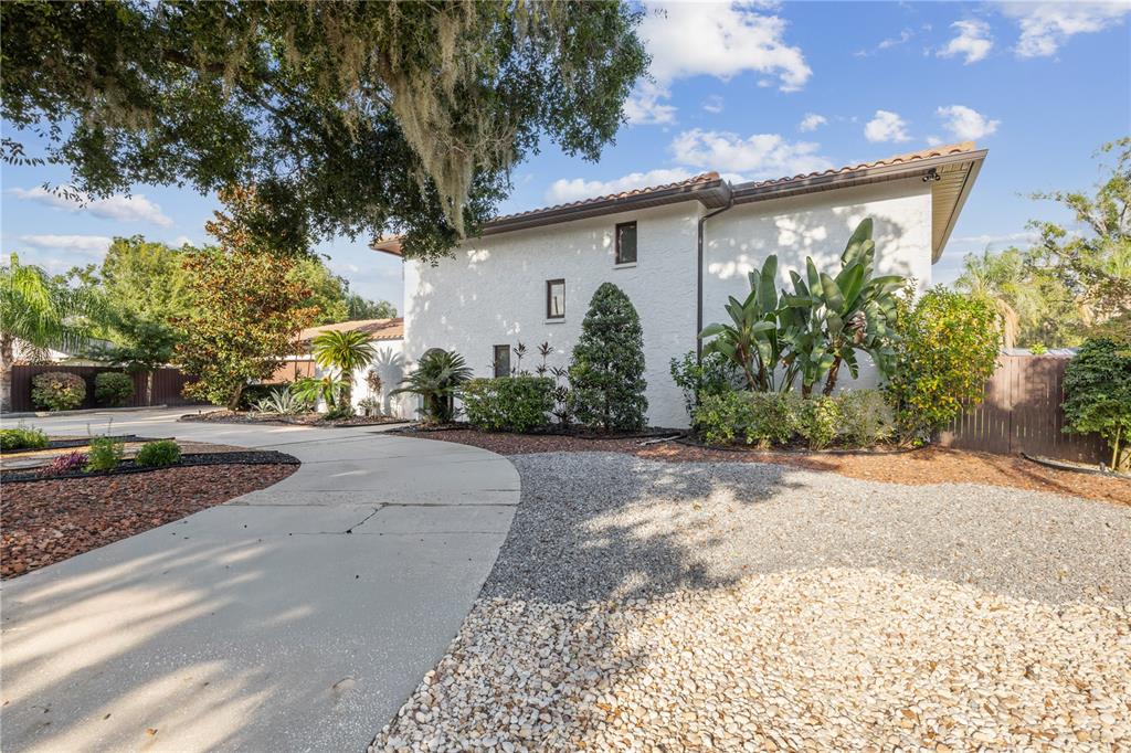A white stucco house with a tiled roof sits behind a curved concrete driveway — 403 WEEBURN ROAD, TEMPLE TERRACE, FL