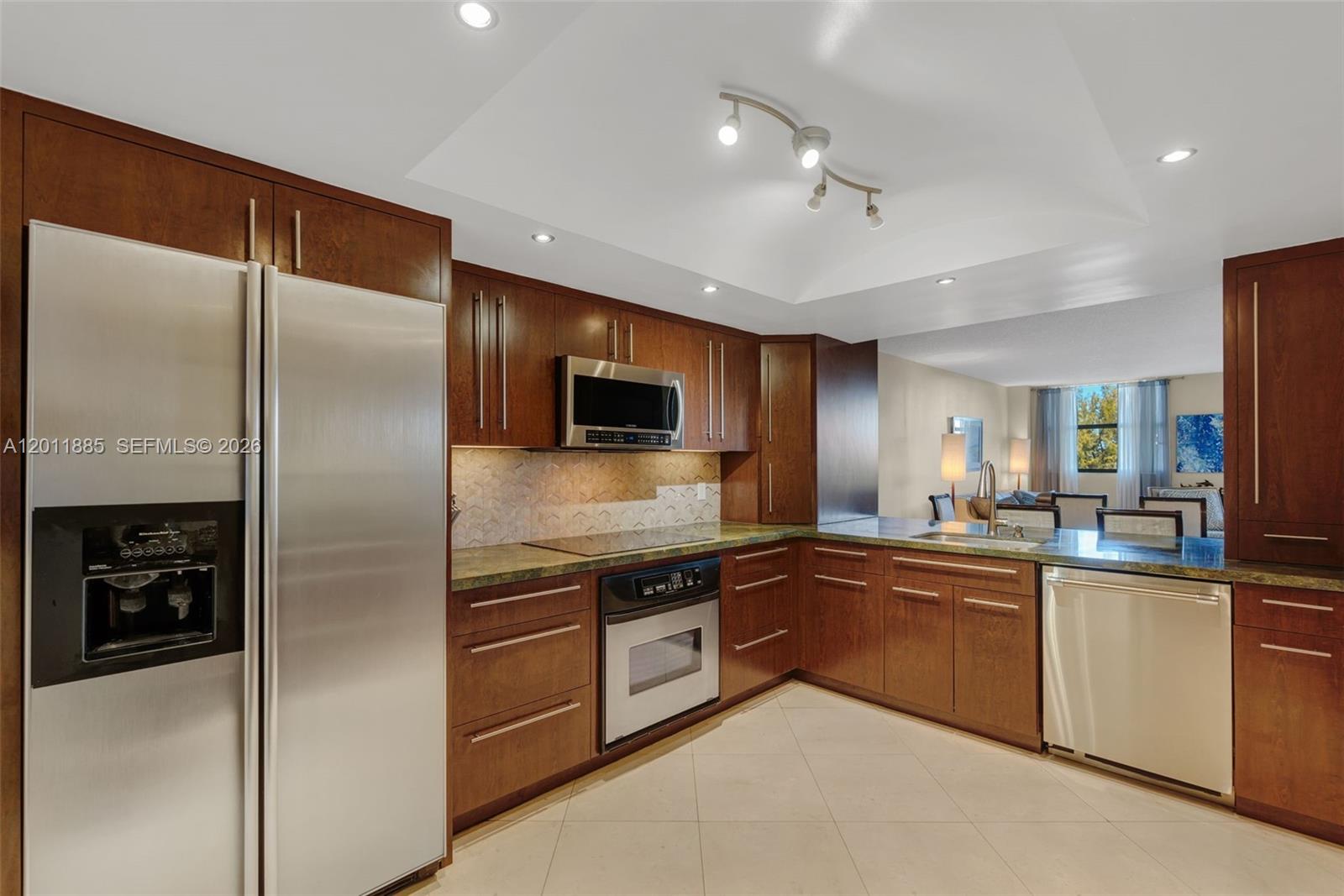 A kitchen features dark wood cabinets, stainless steel appliances, and a green stone countertop — 2900 NE 14th St Cswy # 402, Pompano Beach FL 33062, POMPANO BEACH, FL
