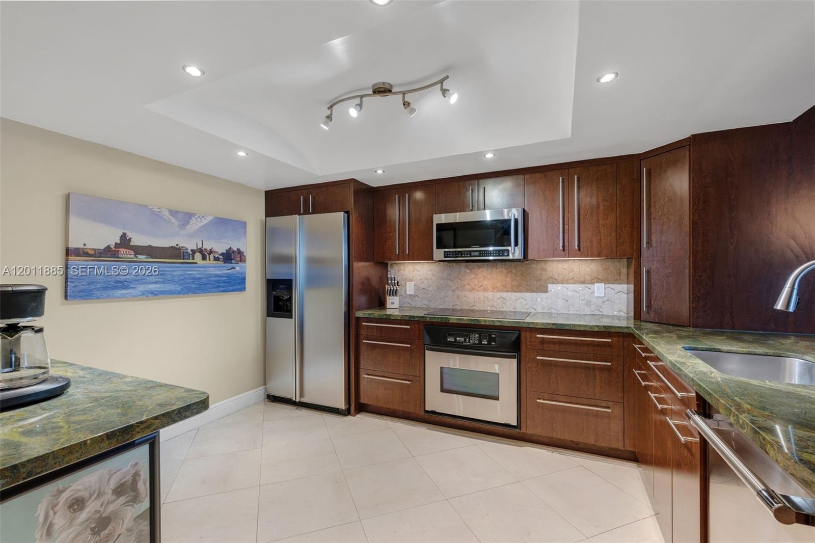 A kitchen features dark wood cabinets, stainless steel appliances, and green granite countertops — 2900 NE 14th St Cswy # 402, Pompano Beach FL 33062, POMPANO BEACH, FL