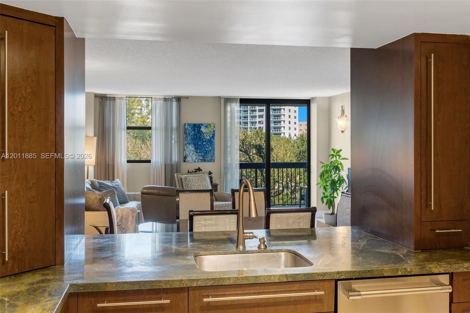 A kitchen island with a sink overlooks a living room with a balcony and view — 2900 NE 14th St Cswy # 402, Pompano Beach FL 33062, POMPANO BEACH, FL