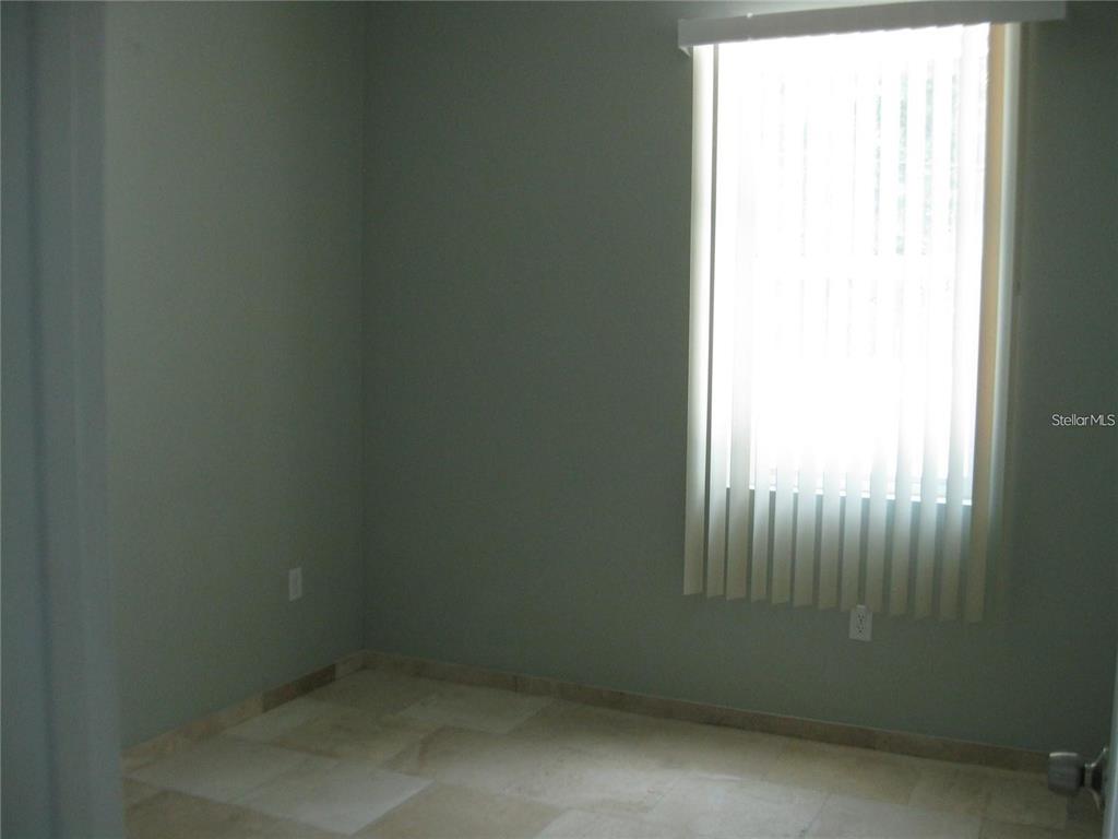 An empty room features light-colored tile flooring, pale green walls, and a window with blinds — 2009 COCOANUT AVENUE UNIT 2, SARASOTA, FL