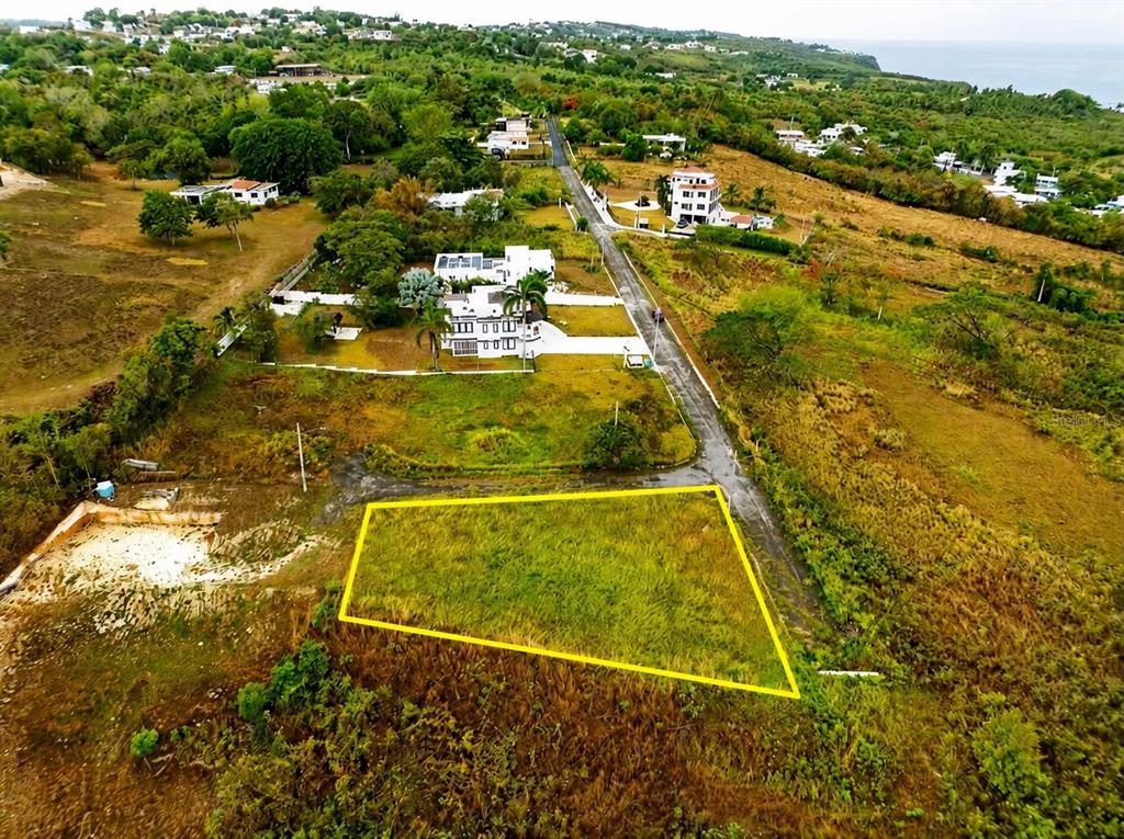 An aerial view shows a vacant, grass-covered rectangular lot outlined in yellow next to a road — Carr. 485 Km HM. 1.5 BO. SAN JOSE SOLAR #8, QUEBRADILLAS, PR
