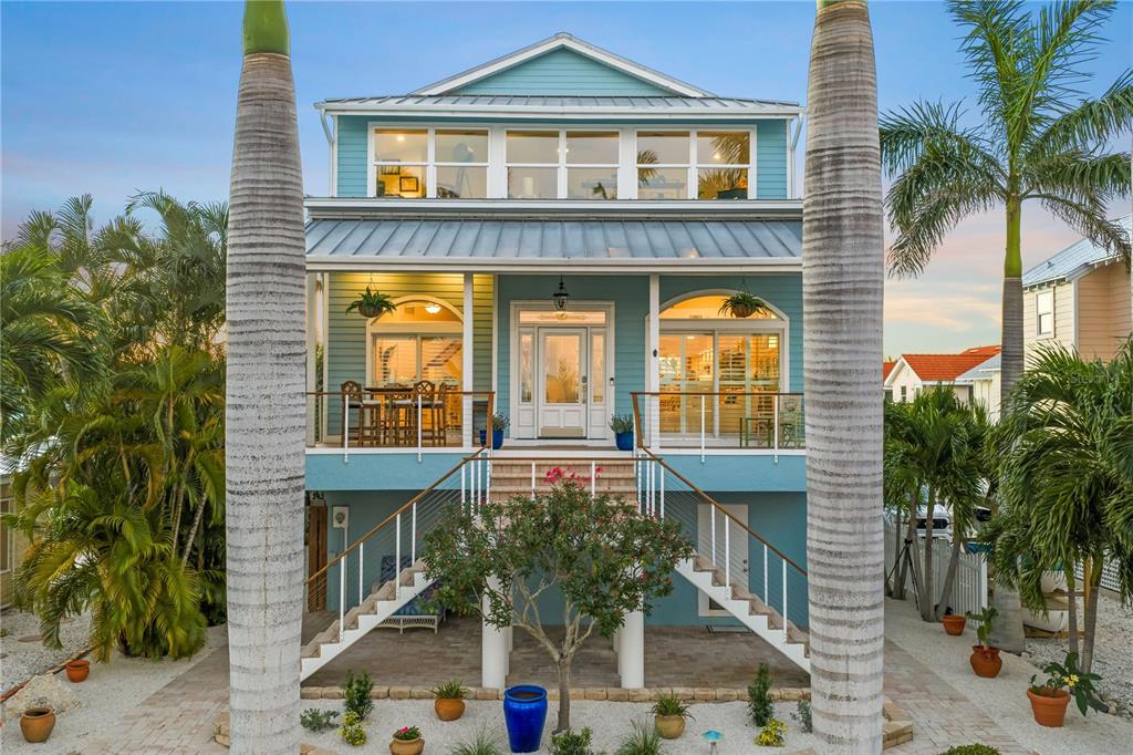 A light blue, elevated two-story coastal home with a front staircase and palm trees — 791 BROADWAY STREET, LONGBOAT KEY, FL
