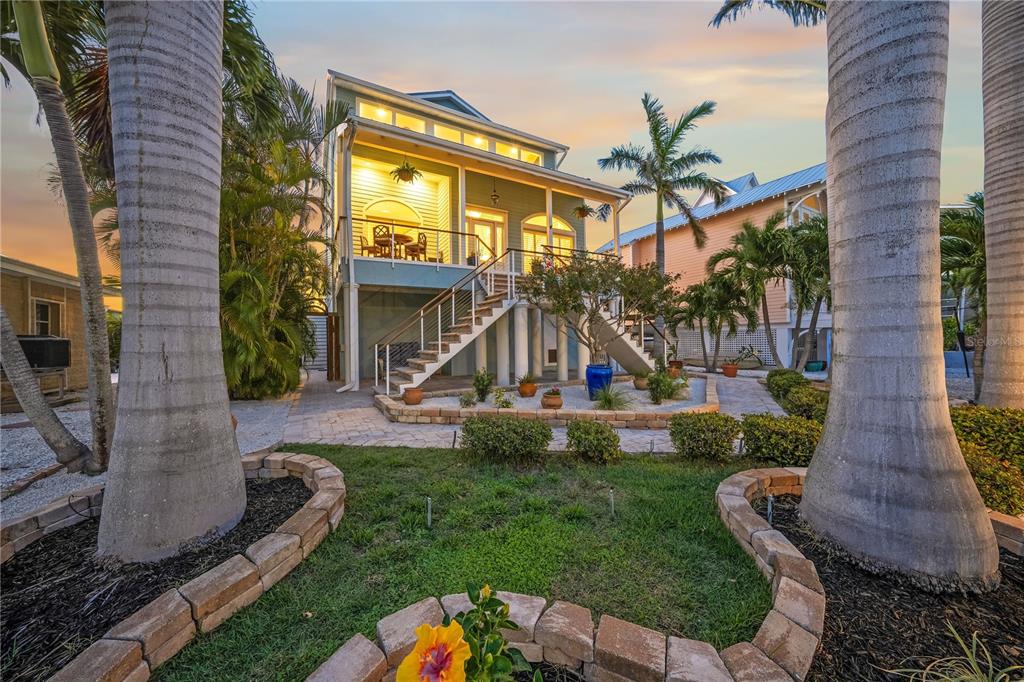 A stilt house with a wooden staircase leading to a balcony and a landscaped yard — 791 BROADWAY STREET, LONGBOAT KEY, FL
